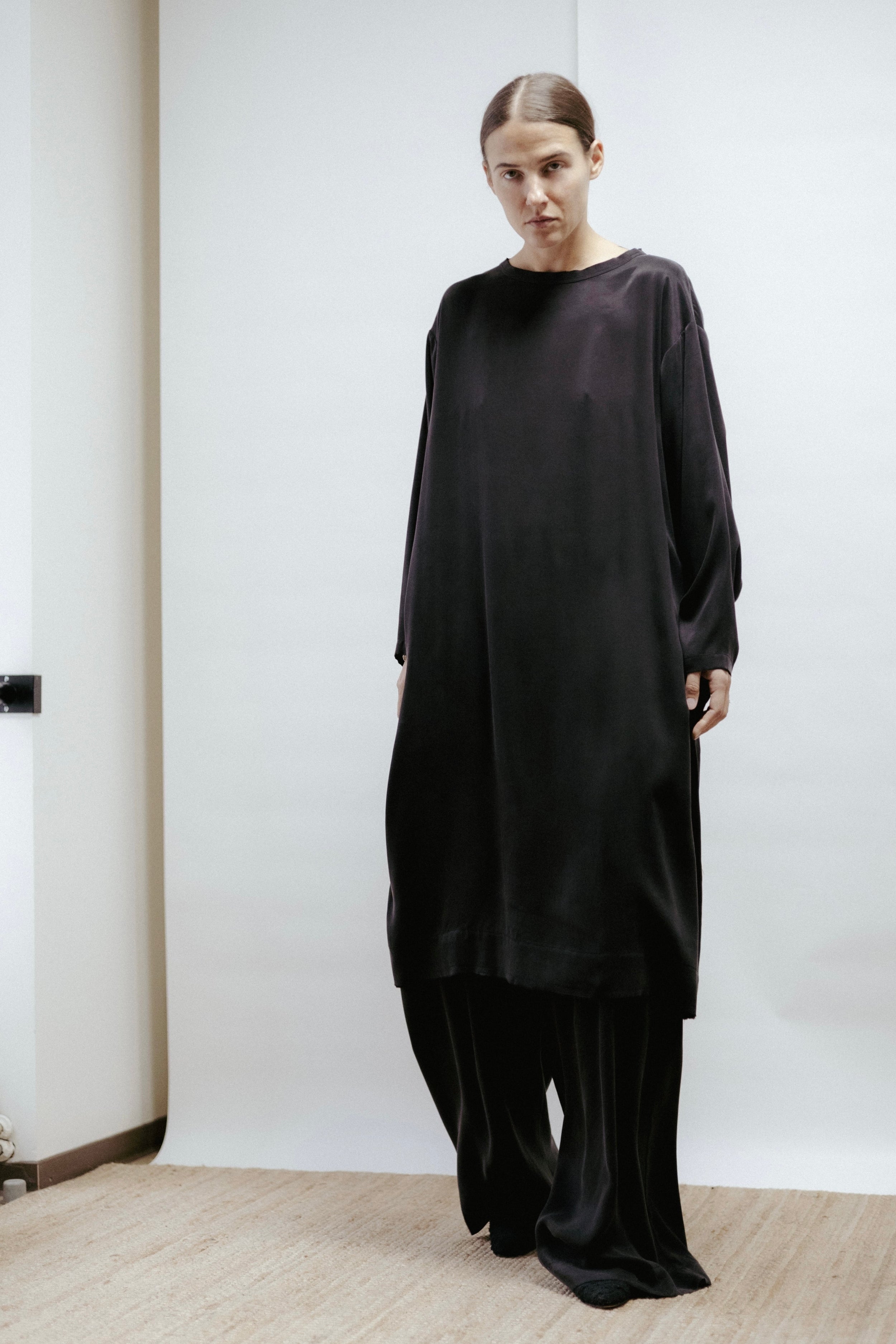 Straight black cupro-viscose dress with boat neckline and raw-cut edges. Can also be worn as a tunic with matching trousers. Made in Estonia.