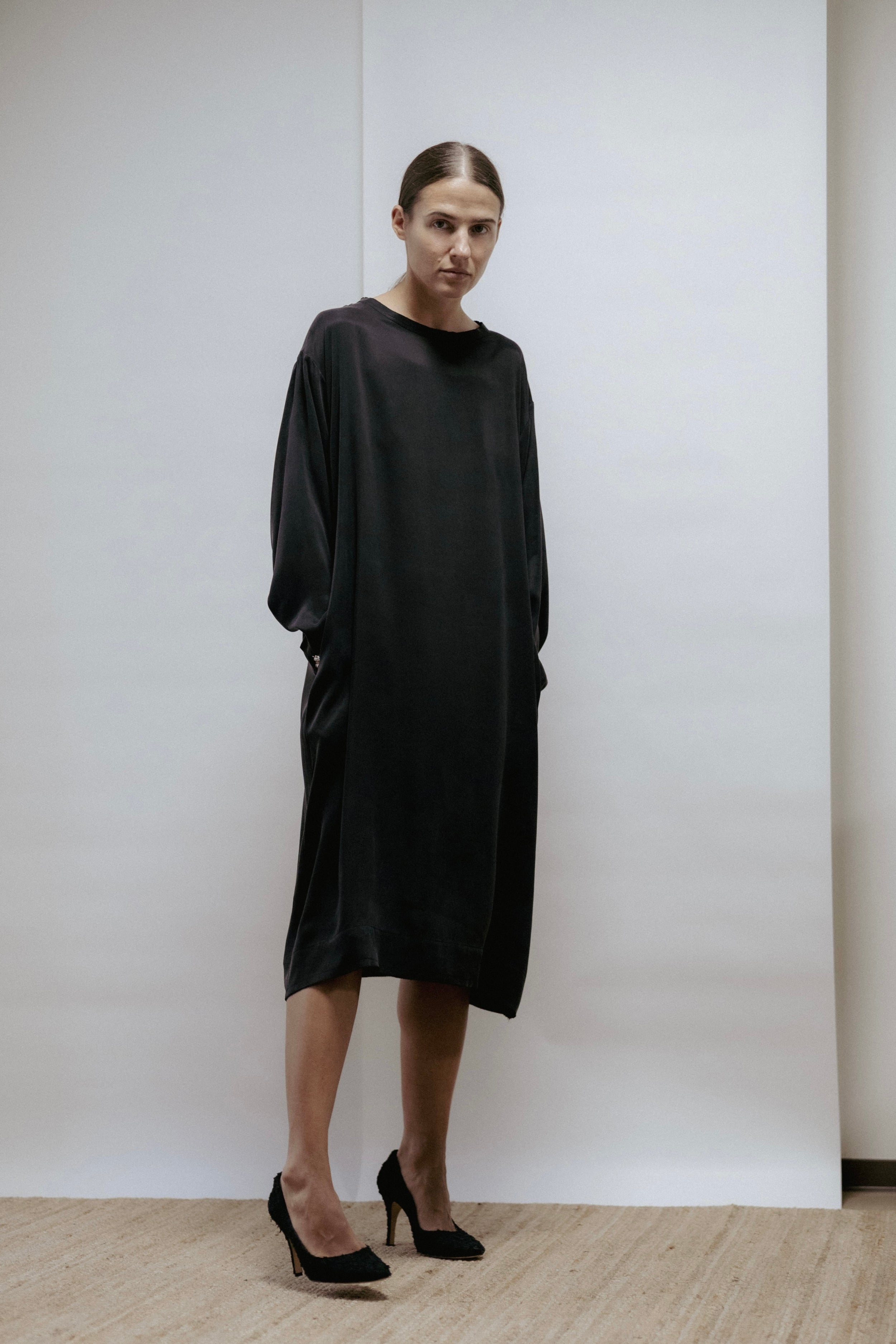Black cupro dress with boat neckline, long sleeves, and raw-cut edges. Relaxed fit, made in Estonia.