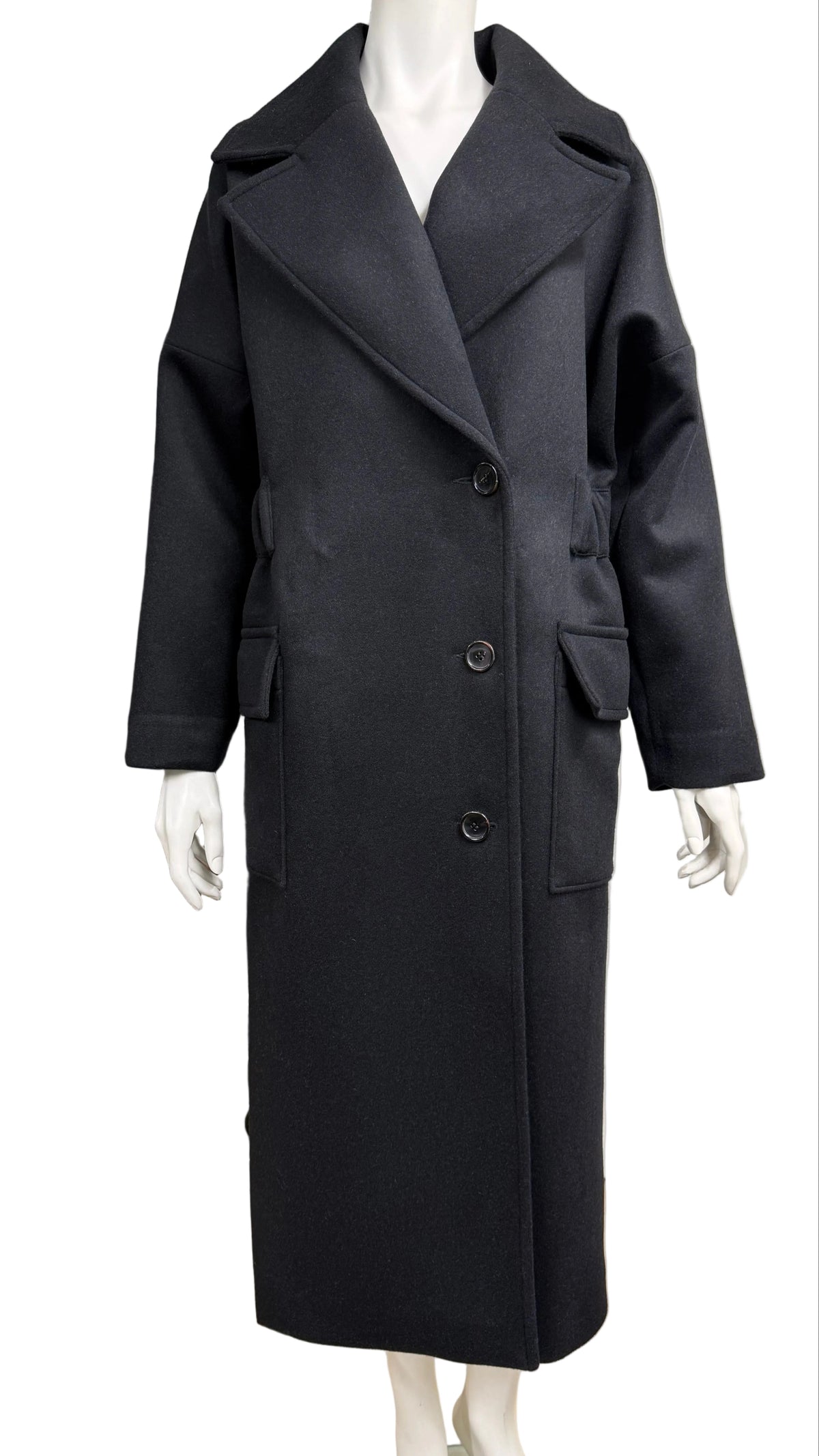 A long black wool-blend coat displayed on a white mannequin. The coat features a double-breasted front with large lapels, wide sleeves, and front patch pockets.