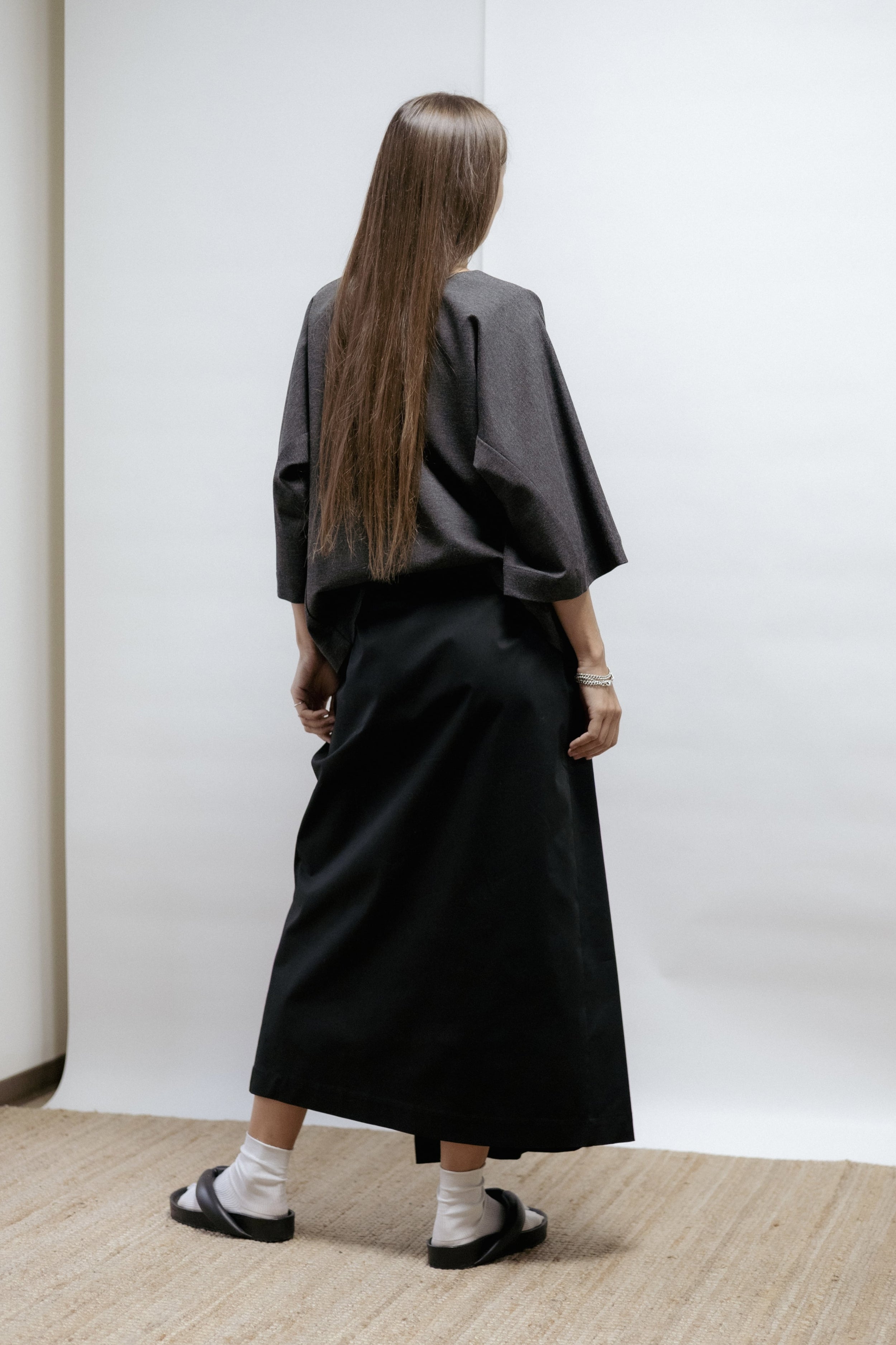 Black cotton wrap skirt with pleated front and adjustable tie. Soft structure, mid-length, and easy care. Made in Estonia.