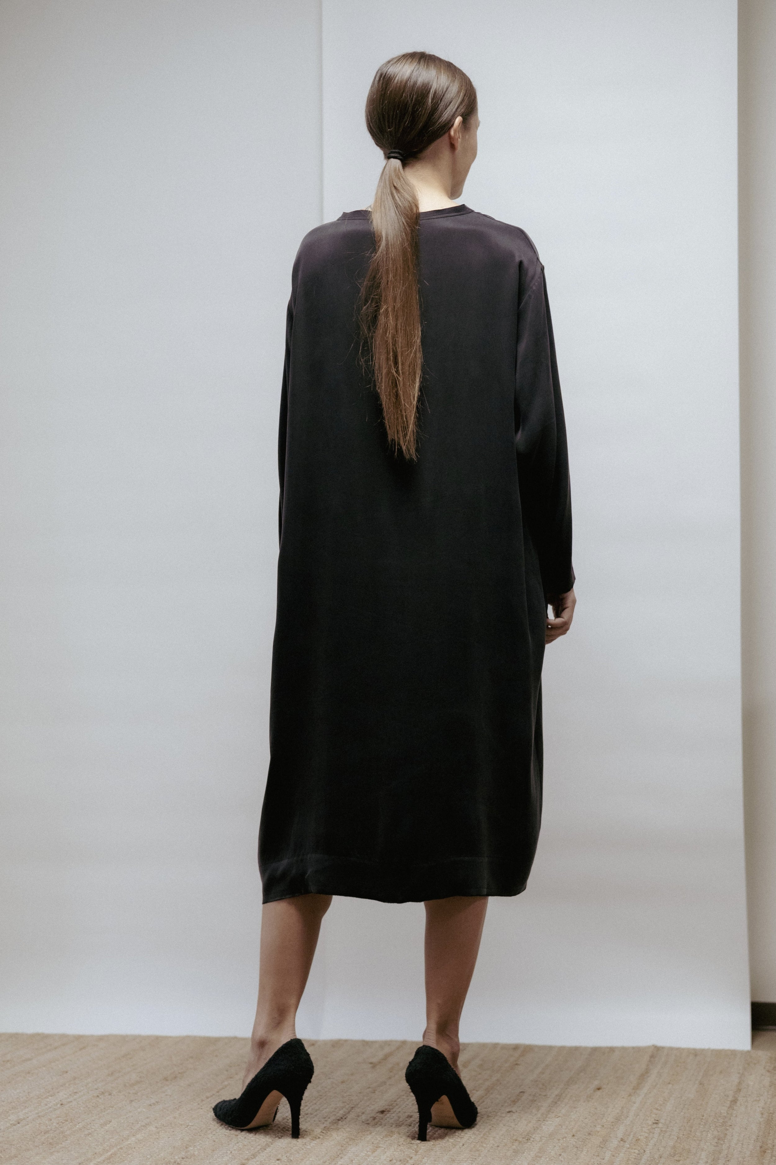 Black cupro dress with boat neckline, long sleeves, and raw-cut edges. Relaxed fit, made in Estonia.