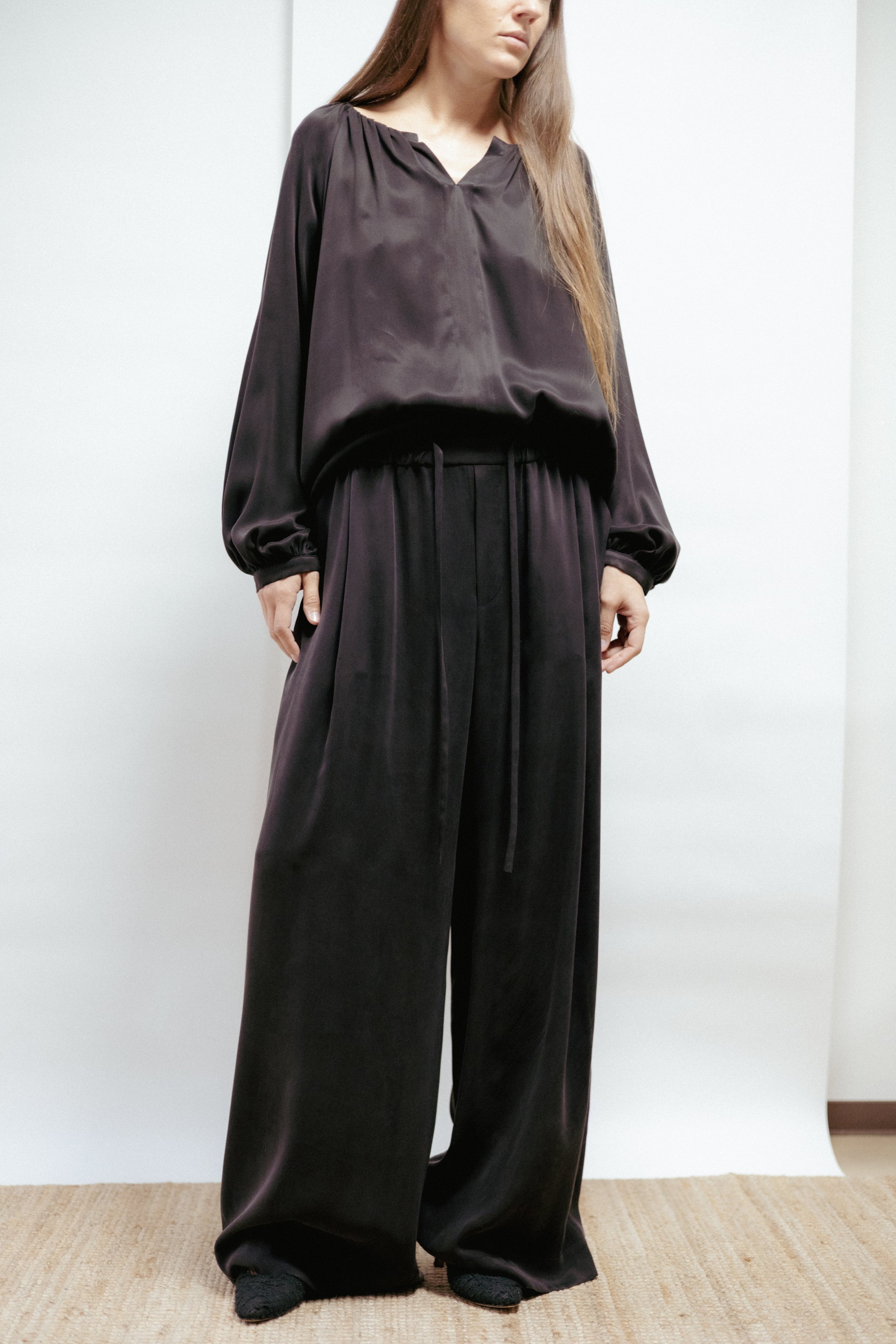 Wide black cupro trousers with adjustable waist and flowing drape. Soft, elegant, and made in Estonia.