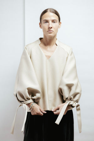 Light gold blouse with voluminous sleeves and a refined stand collar. Non-creasing textured fabric. Made in Estonia.