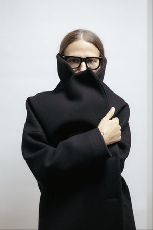 Black wool coat with wide lapel collar and relaxed fit. Midi length, warm lining, and refined simplicity. Made in Estonia.