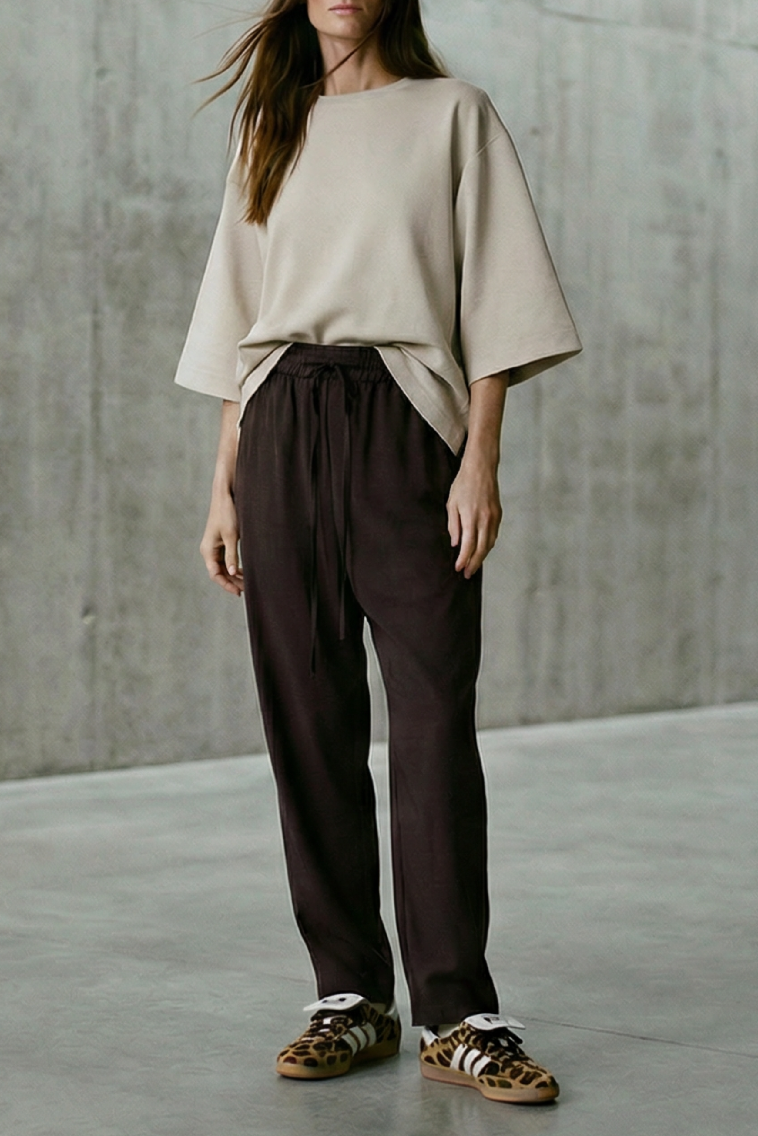 Woman standing in a minimalist room with concrete walls and floor.