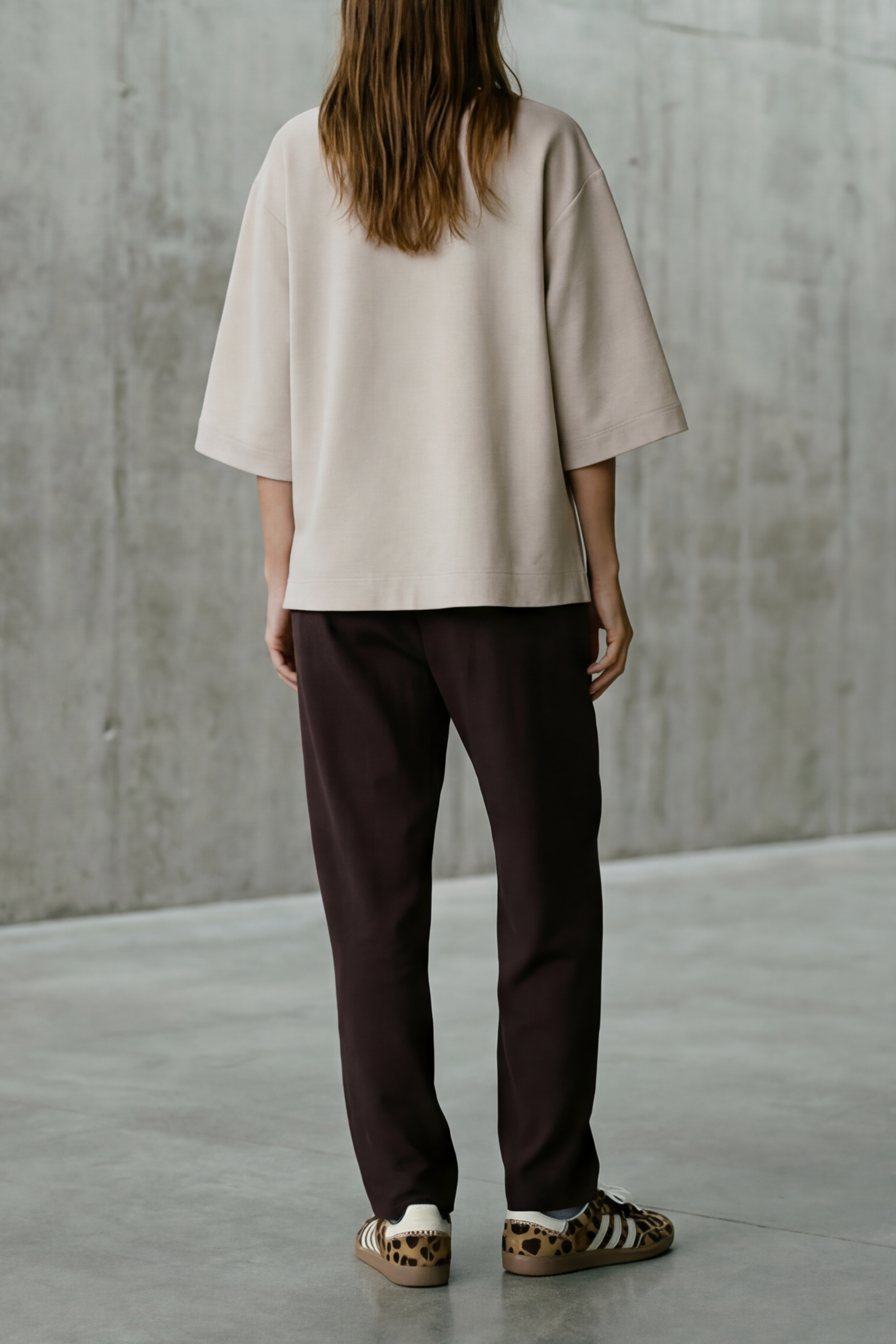 Person standing in a minimalist room with concrete walls and floor.