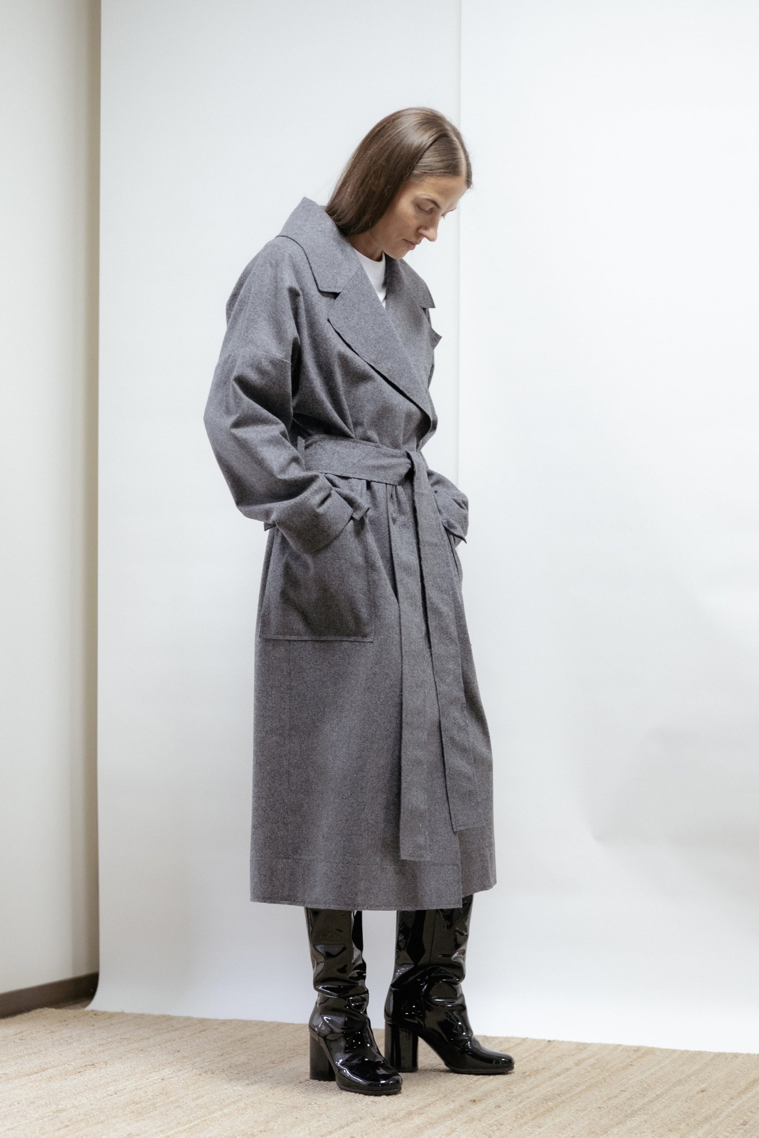 A timeless grey wool coat crafted from pure wool with raw-cut edges and a self-tie belt. Partially lined in cotton sleeves for comfort and movement.