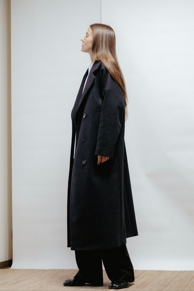 Dark grey wool coat with a wide lapel collar and slanted pockets. Straight, relaxed fit with back vent and light lining. Made in Estonia.