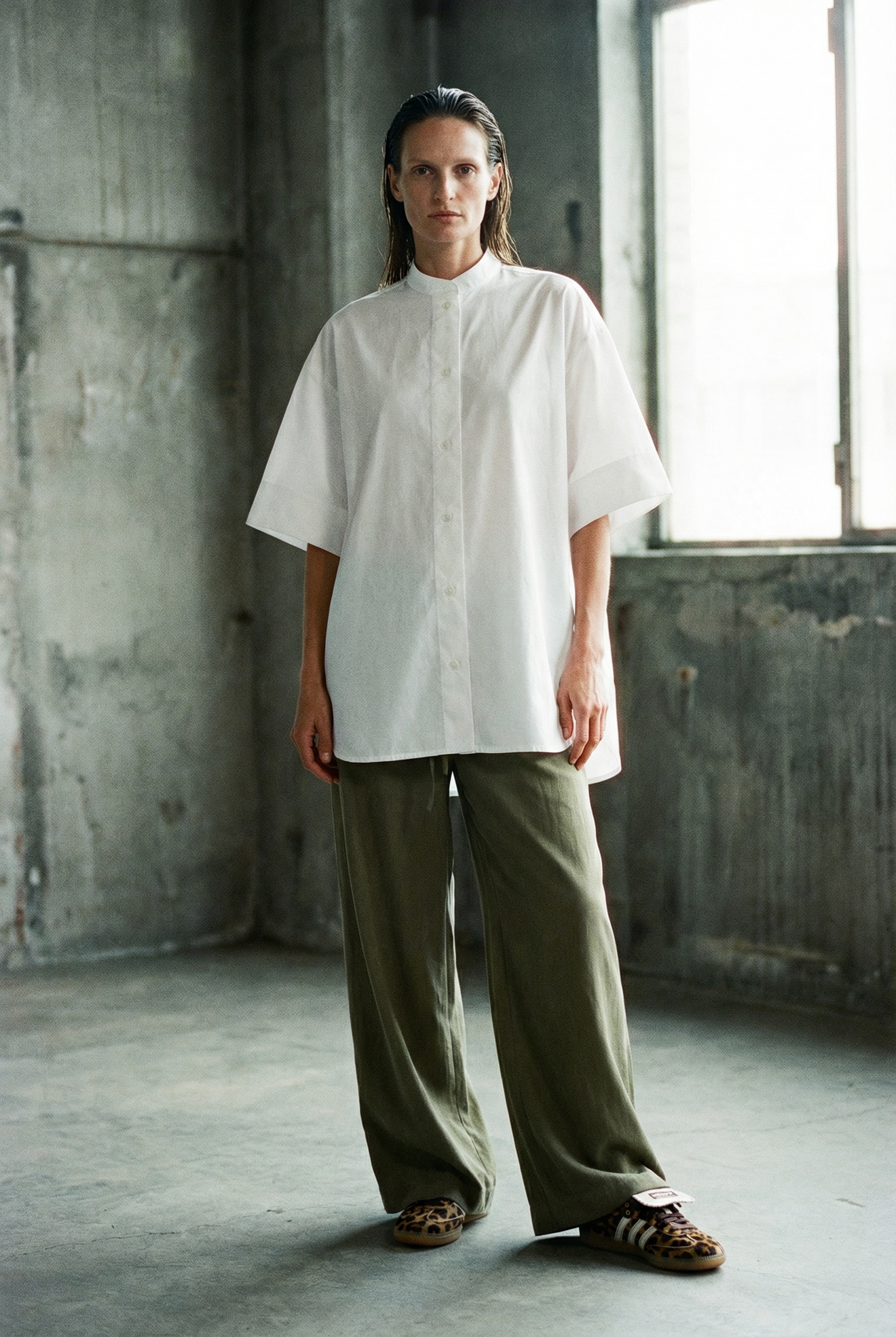 Person wearing a white shirt and green pants in an industrial setting
