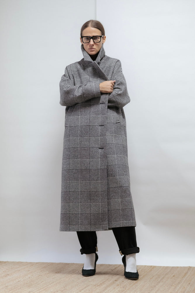Checked wool coat in black, white, and grey. Oversized shape, midi length, and warm lining. Timeless comfort. Made in Estonia.