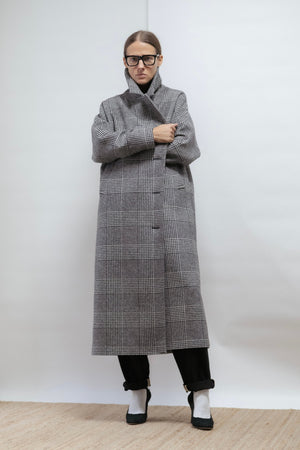 Checked wool coat in black, white, and grey. Oversized shape, midi length, and warm lining. Timeless comfort. Made in Estonia.
