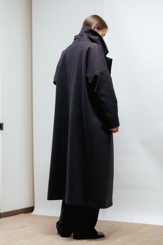 Dark grey wool coat with wide lapel, relaxed fit, and back vent. Elegant warmth and timeless structure. Made in Estonia.