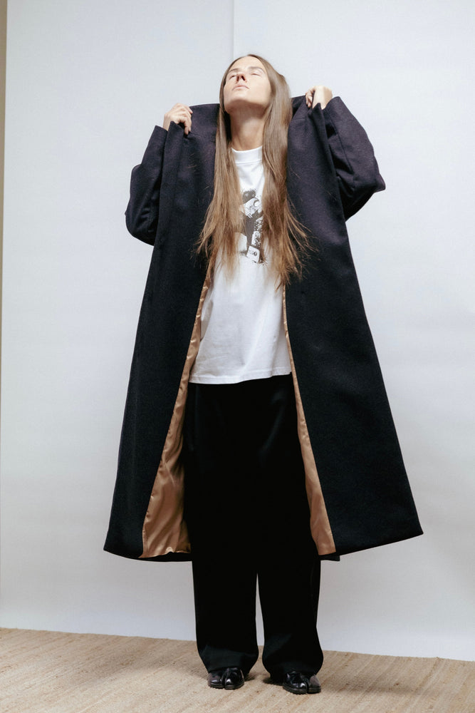 Dark grey wool coat with wide lapel, relaxed fit, and back vent. Elegant warmth and timeless structure. Made in Estonia.