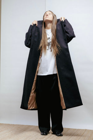 Dark grey wool coat with wide lapel, relaxed fit, and back vent. Elegant warmth and timeless structure. Made in Estonia.